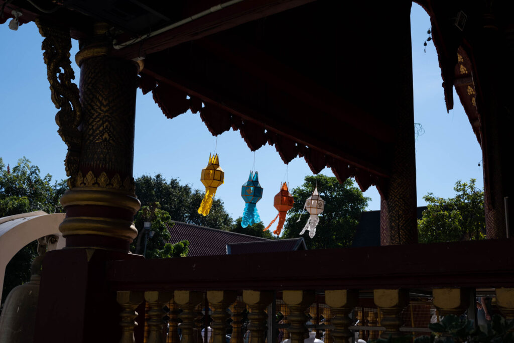 Some colorful lanterns, blowing in the wind, at the entrance of a buddhist temple in Chiang Mai, Thailand.