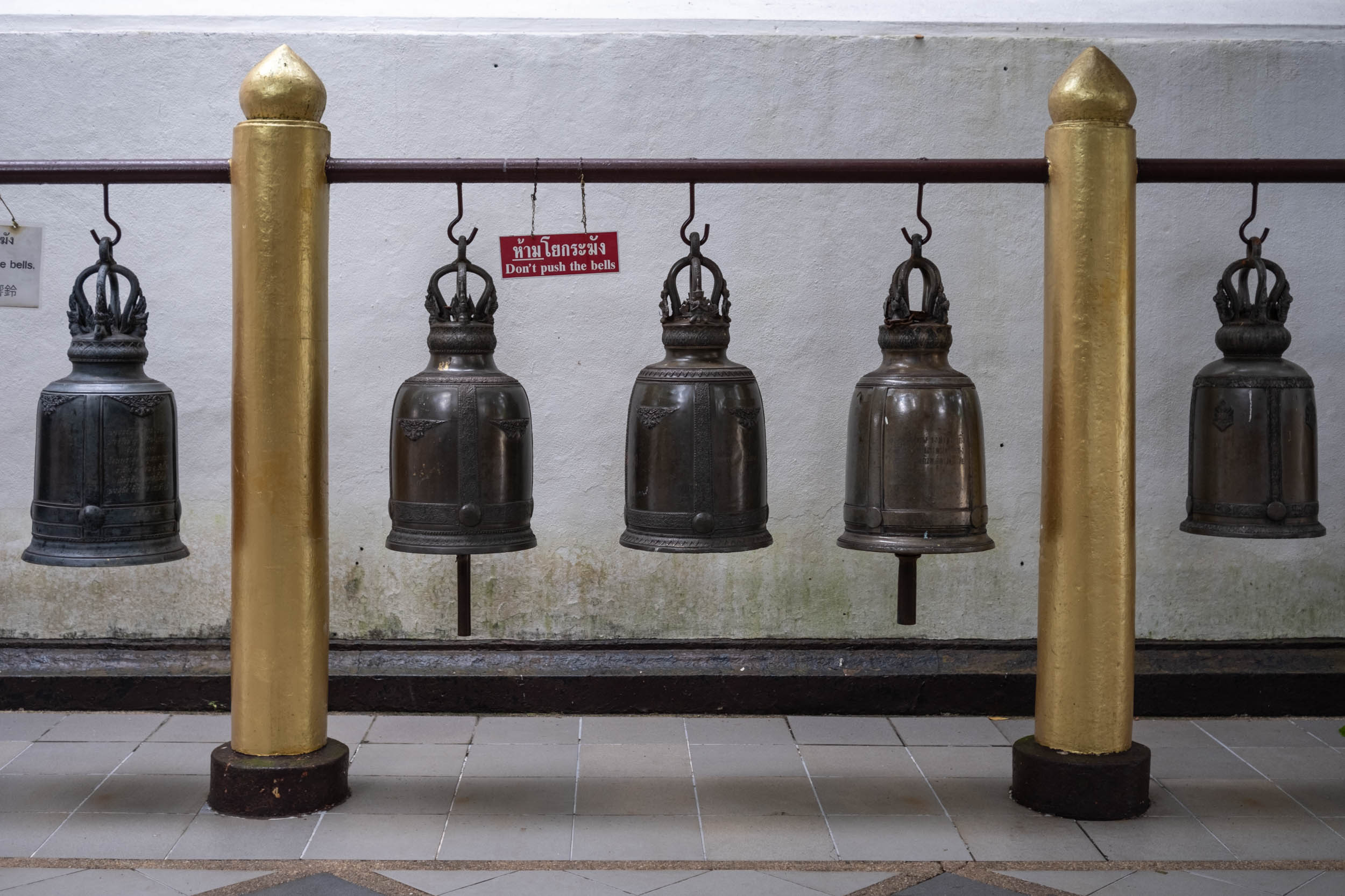 A sign next to some big bells reading "Don't push the bells" at the buddhist temple Wat Phra That Doi Suthep in Chiang Mai.