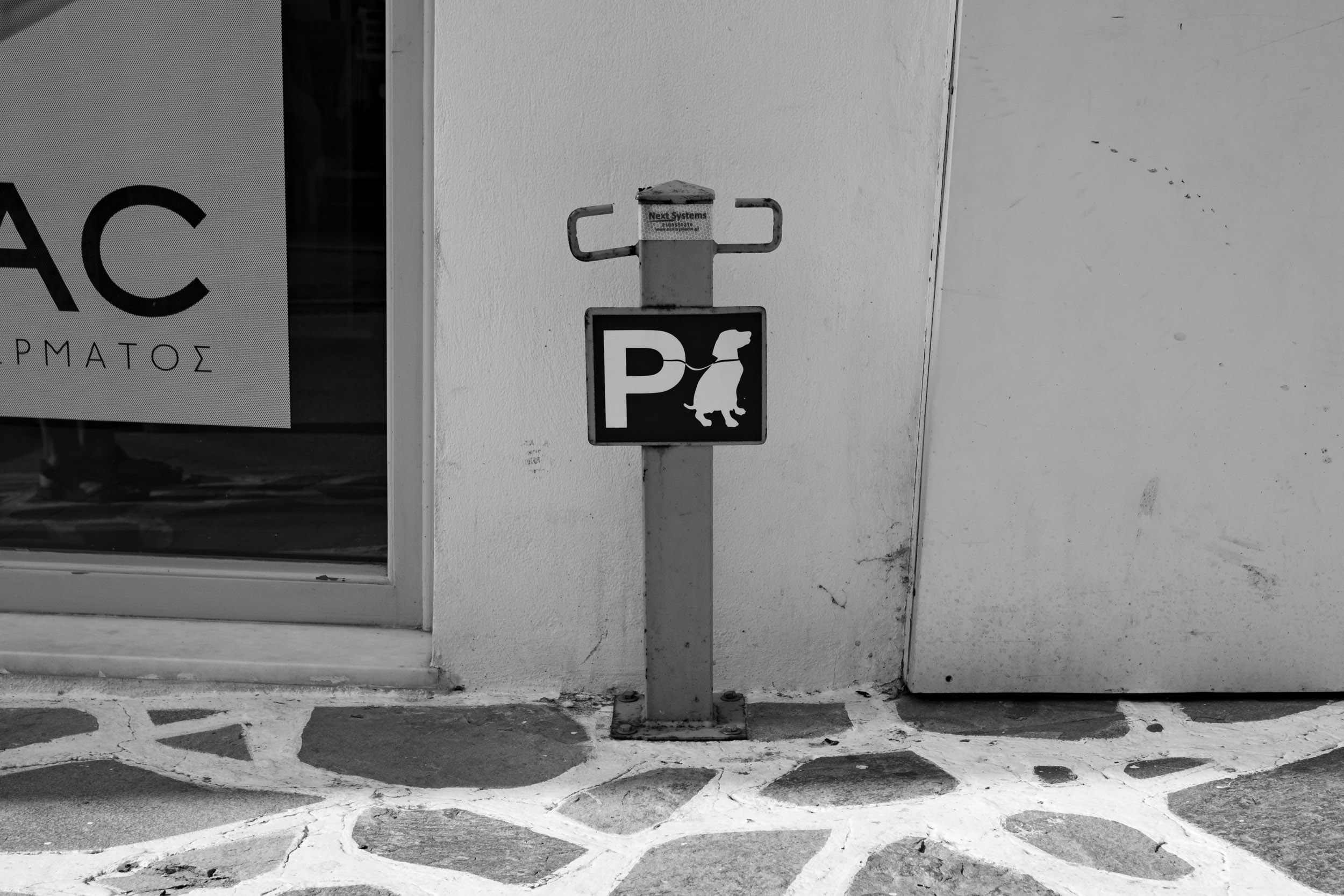 A sign for the "Dog Parking" spot in front of a shop in Naxos, Greece.