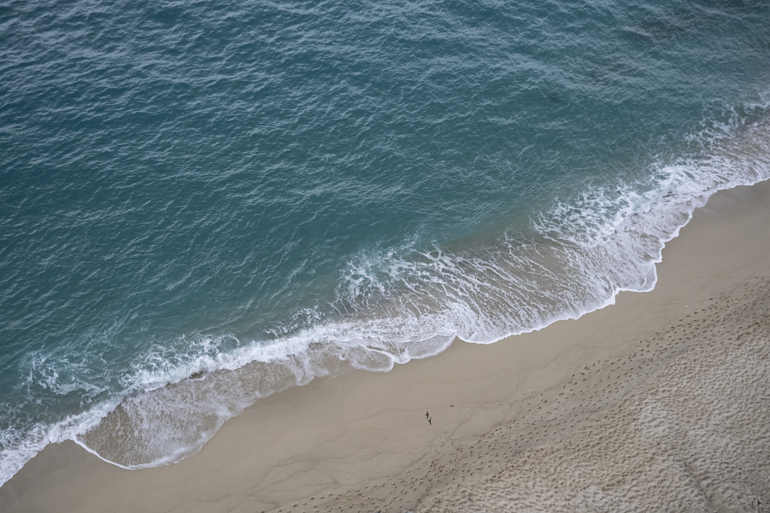Beautiful beach of Tropea from above, with waves breaking in the sand.