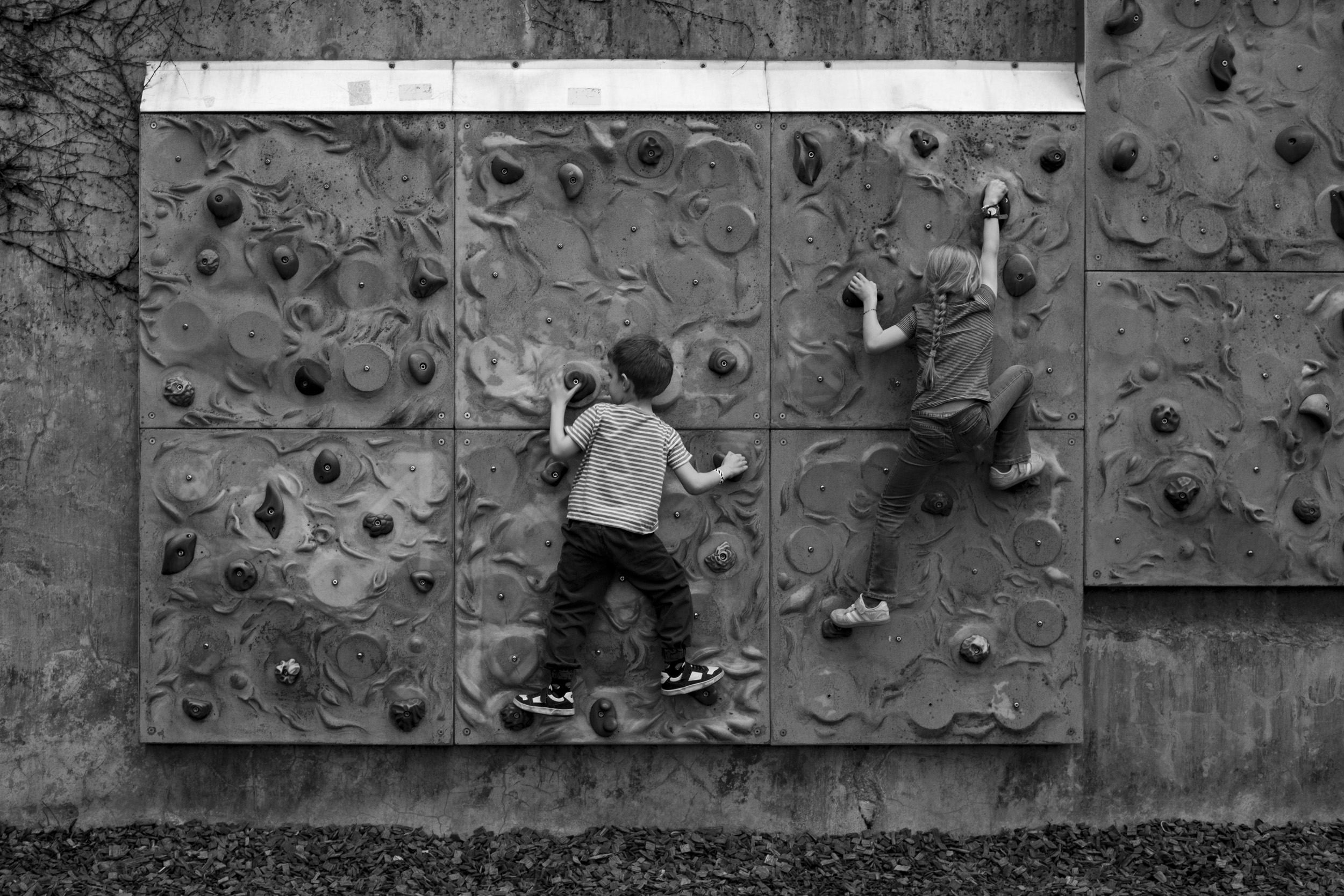 Kids climbing a small playground boulder wall at the Zoo.