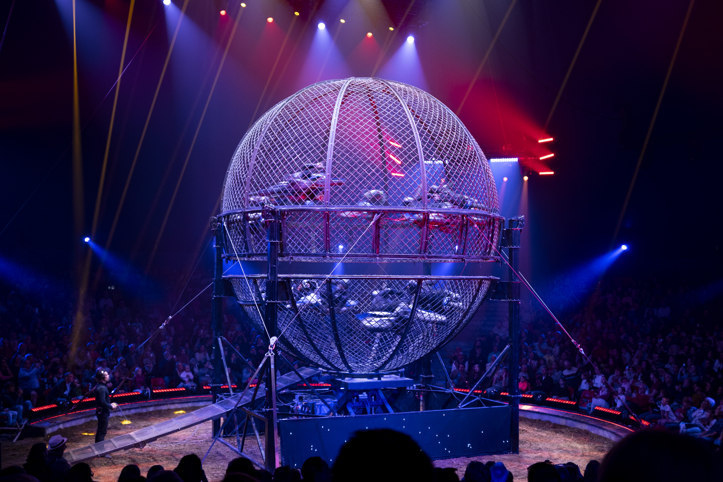 10 people driving on motorcycles  racing around the inside of a giant steel "Globe of Death", a performance at the Circus Knie this Sunday.