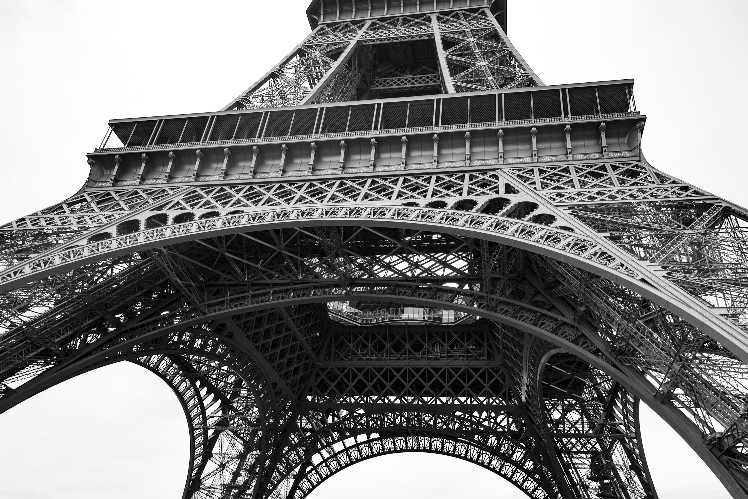 Eiffel Tower shot from underneath, in black and white. In the center, you see the first balcony with the names of 72 scientists (all male) engraved on the outside.