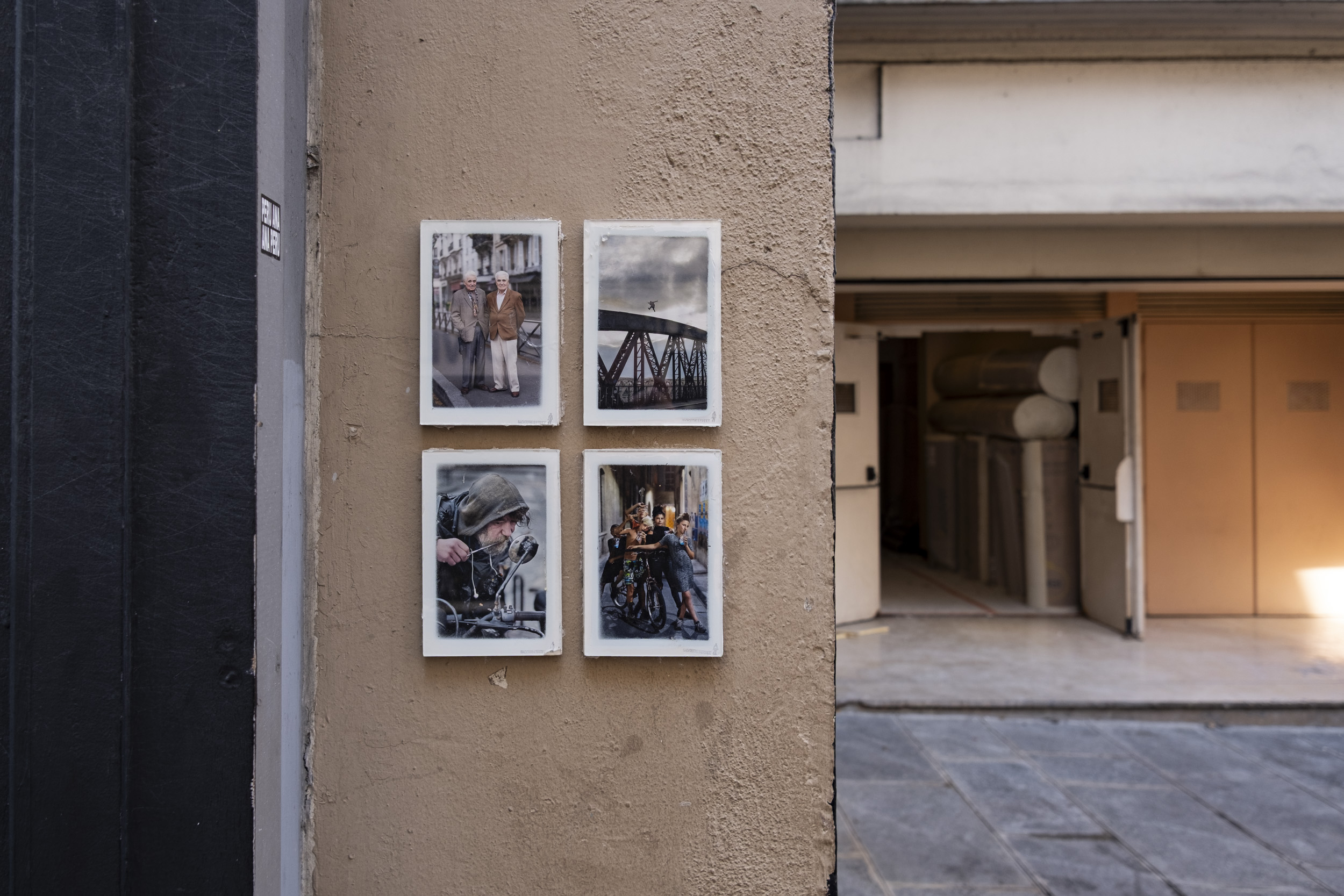 Four framed photos on a wall in the streets of Paris, putting street photography back to the streets.