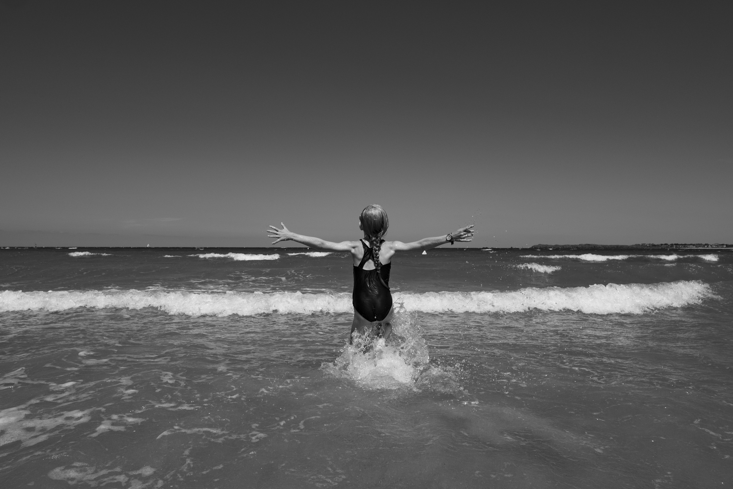 My daughter, spreading her arms wide, while running into the waves.