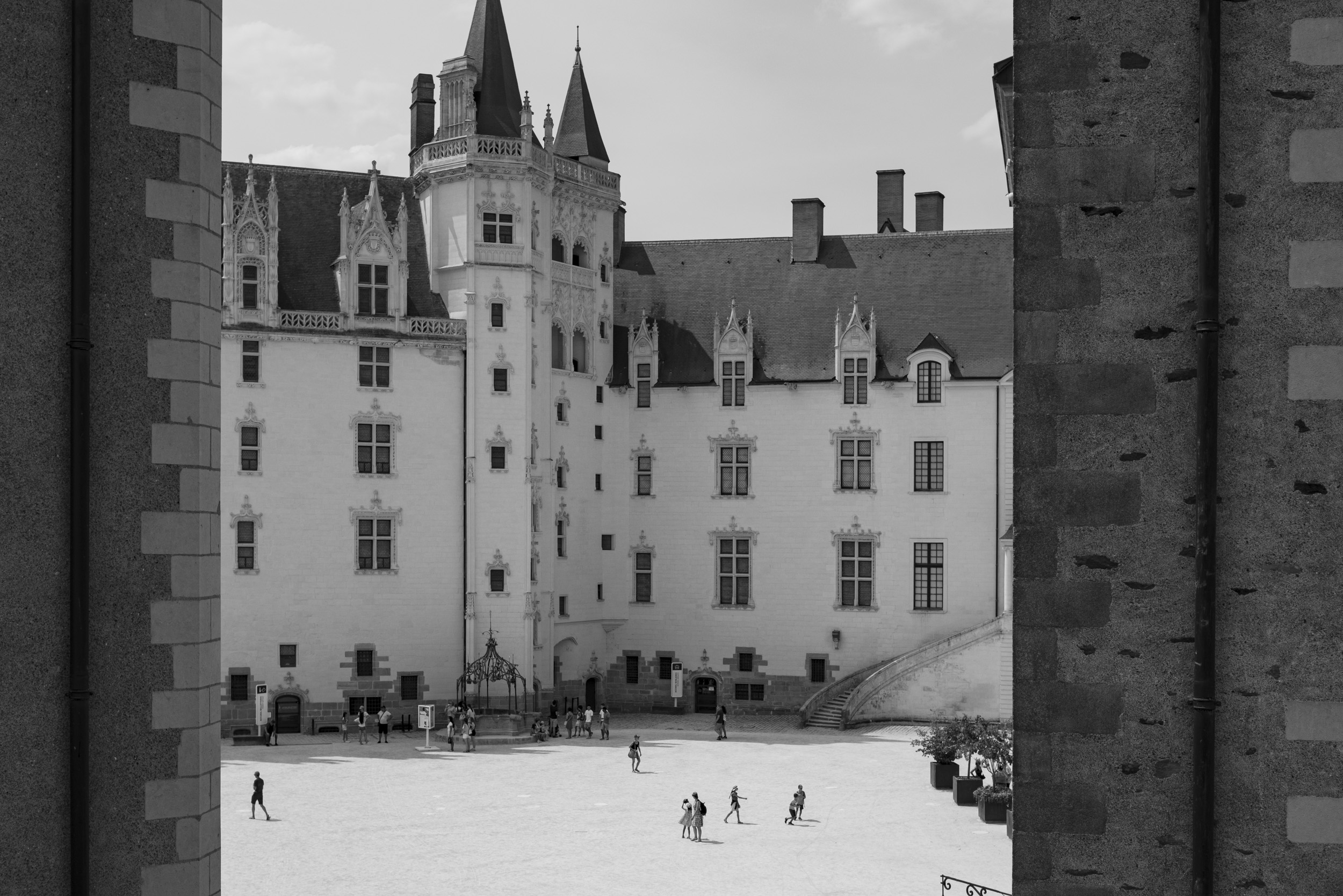 The Château des ducs de Bretagne (Castle of the Dukes of Brittany) viewed through the walls on the other side, with people walking on the courtyard.
